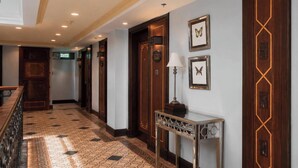 A hotel hallway with wooden doors, a reception desk, and framed artwork on the walls. - Herald Suites Polaris (Makati)