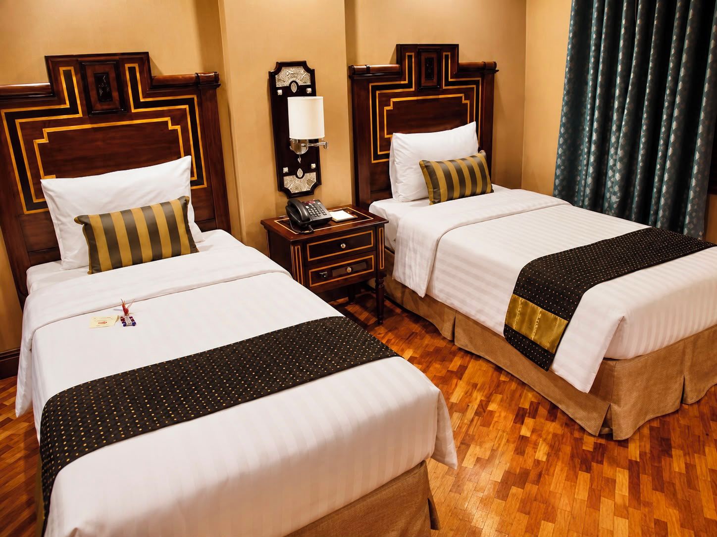Habitación de hotel con dos camas, una mesita de noche con teléfono y una lámpara fijada a la pared.