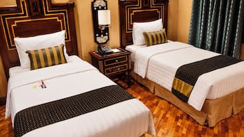 Habitación de hotel con dos camas, una mesita de noche con teléfono y una lámpara fijada a la pared.
