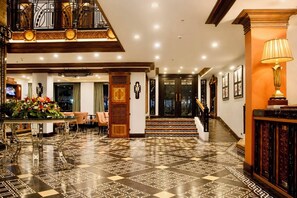 A hotel lobby with a checkered floor, a staircase, and a seating area with chairs and a table. - Herald Suites Polaris (Makati)