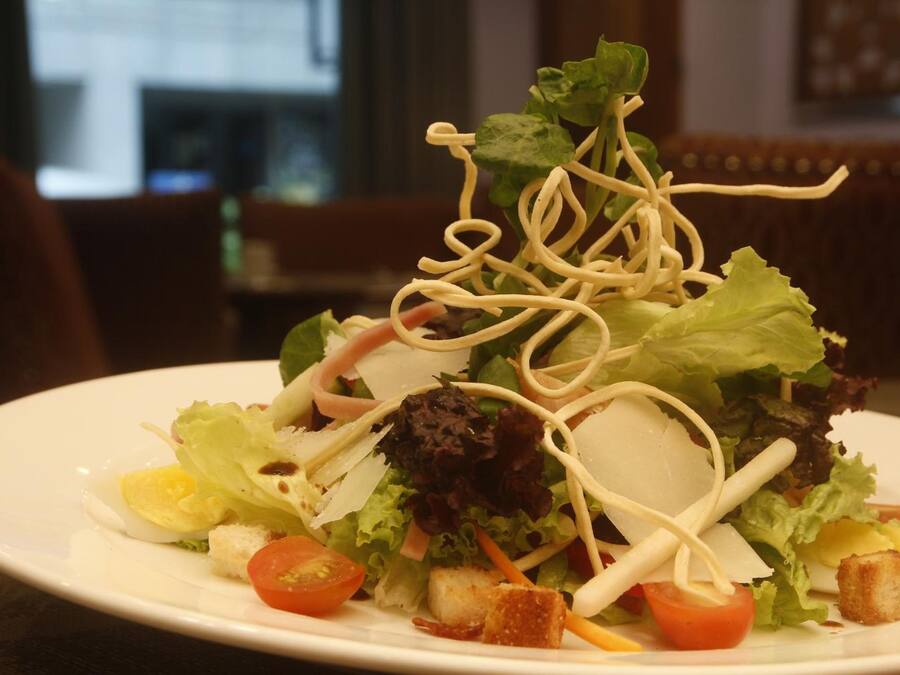 A plate of salad with various vegetables and croutons.