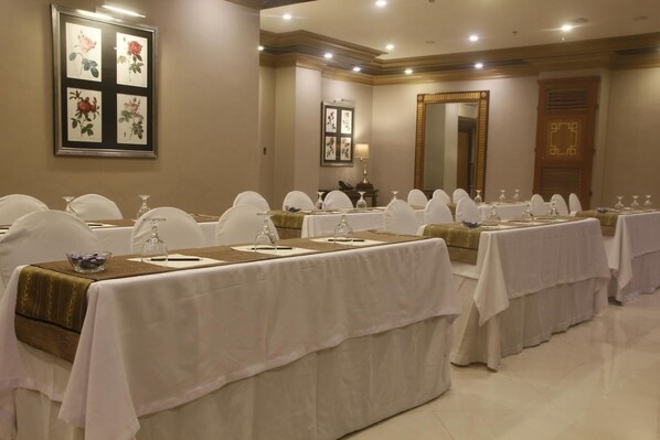 A conference room with long tables, white chairs, and floral wall art. - Herald Suites Polaris (Makati)