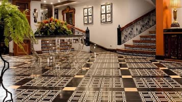 Un vestíbulo amplio con un estampado de piso a cuadros, una escalera y una barandilla decorativa.