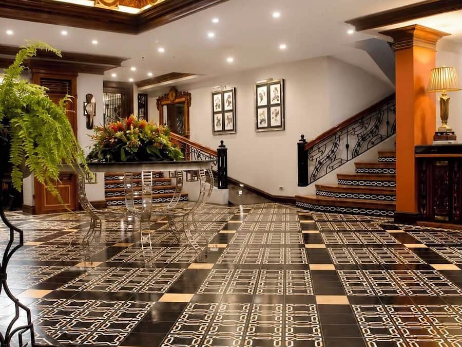 A spacious lobby with a checkered floor pattern, a staircase, and a decorative railing.