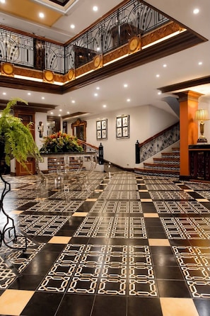 A spacious lobby with a checkered floor pattern, a staircase, and a decorative railing. - Herald Suites Polaris (Makati)