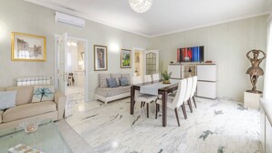 A spacious living area with a dining table, sofa, and a television.