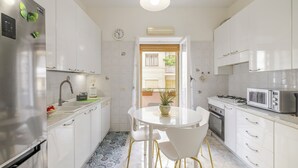 A modern kitchen with white cabinets, stainless steel appliances, and a dining area with a white table and chairs.