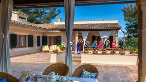 Uma área de pátio com móveis de vime, uma mesa posta com jarra, copos e bule.