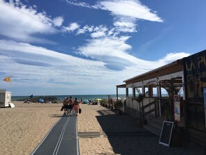 Een restaurant aan het strand met een overdekt terras, een bewakingspost en een helder uitzicht op de oceaan.