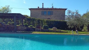 Uma piscina azul cristalina com um edifício de pedra ao fundo.
