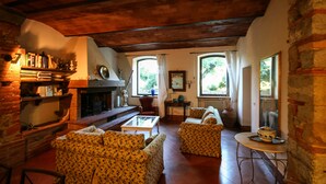 Uma sala de estar acolhedora com sofás estampados, lareira e estante de livros.