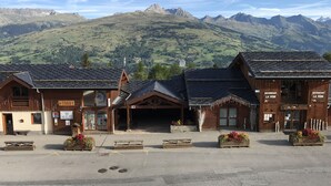 A mountain lodge with a parking area, wooden buildings, and a view of the surrounding mountains. -  Les Coches / Plagne Tarentaise resort center comfortable apartment 4/5 people (La Plagne Tarentaise)