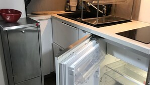 A compact kitchen with a stainless steel refrigerator, a built-in oven, and a sink with a drying rack. -  Les Coches / Plagne Tarentaise resort center comfortable apartment 4/5 people (La Plagne Tarentaise)