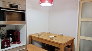 A small kitchen with wooden cabinets, a microwave, a coffee maker, and a table with cups and a bowl. -  Les Coches / Plagne Tarentaise resort center comfortable apartment 4/5 people (La Plagne Tarentaise)