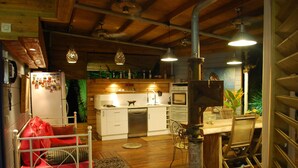 A cozy kitchen with wooden cabinets, a dining area with a table and chairs, and a red sofa. - Luxury villa with pool on an ancient sugarcane plantation (LAMENTIN)