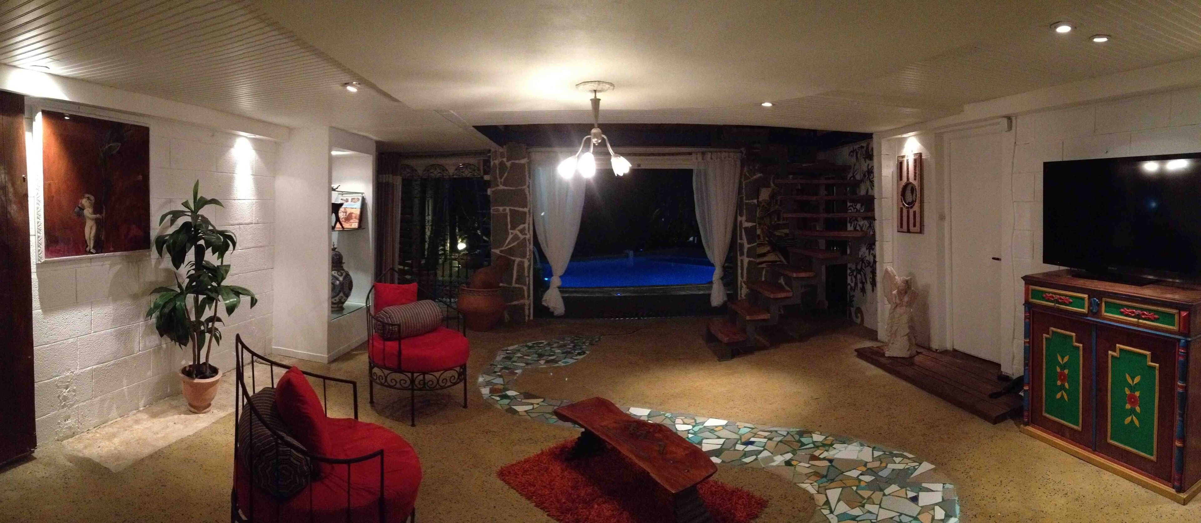 Un salon équipé d’un téléviseur, d’un coin salon et offrant une vue sur une piscine.