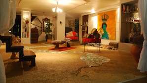 A cozy living room with a fireplace, a red sofa, and a large painting of a woman with a crown. - Luxury villa with pool on an ancient sugarcane plantation (LAMENTIN)