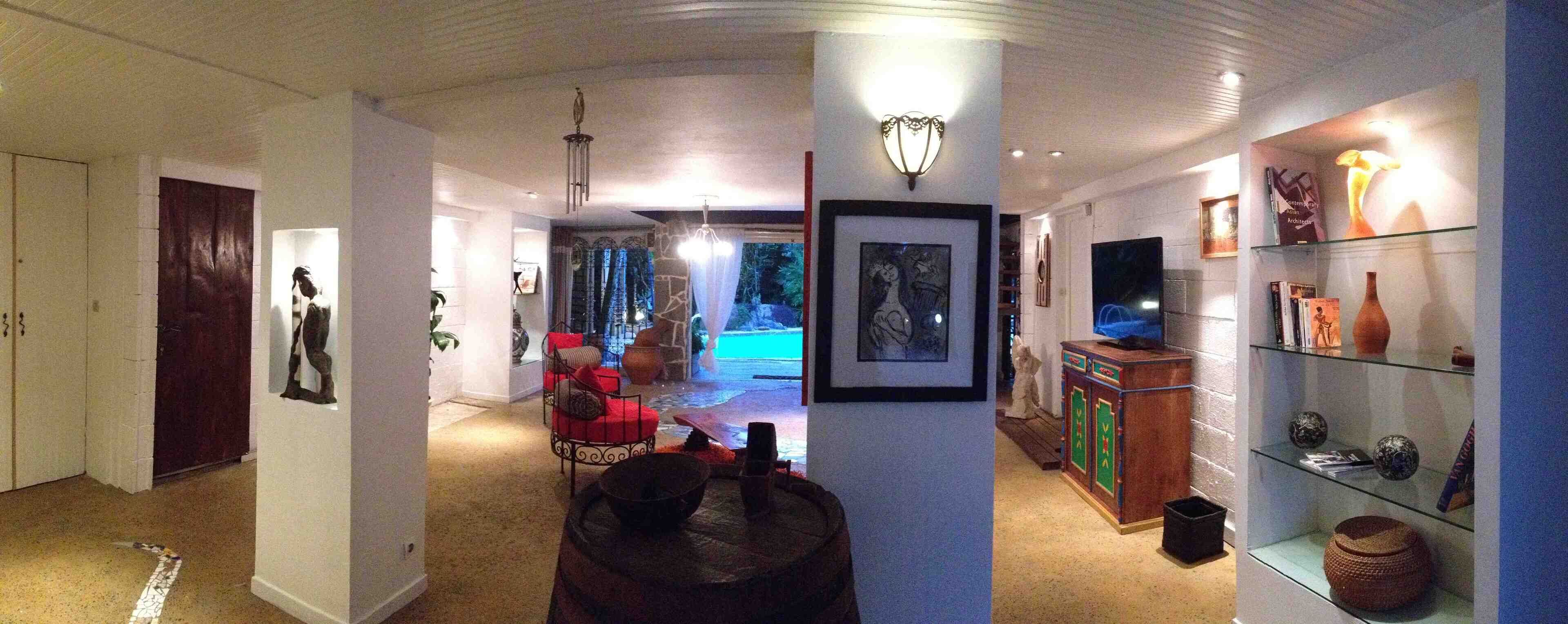 Un couloir comprenant un tonneau en bois, une œuvre d’art encadrée, un téléviseur et une vitrine en verre contenant des objets décoratifs.