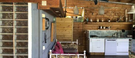 A rustic cabin interior with a bunk bed, kitchenette, and wooden beams.