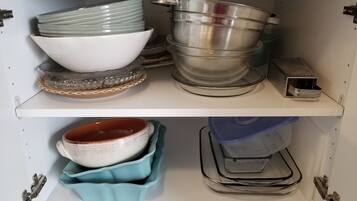 Un armario de cocina con estantes que contienen distintos utensilios de cocina.