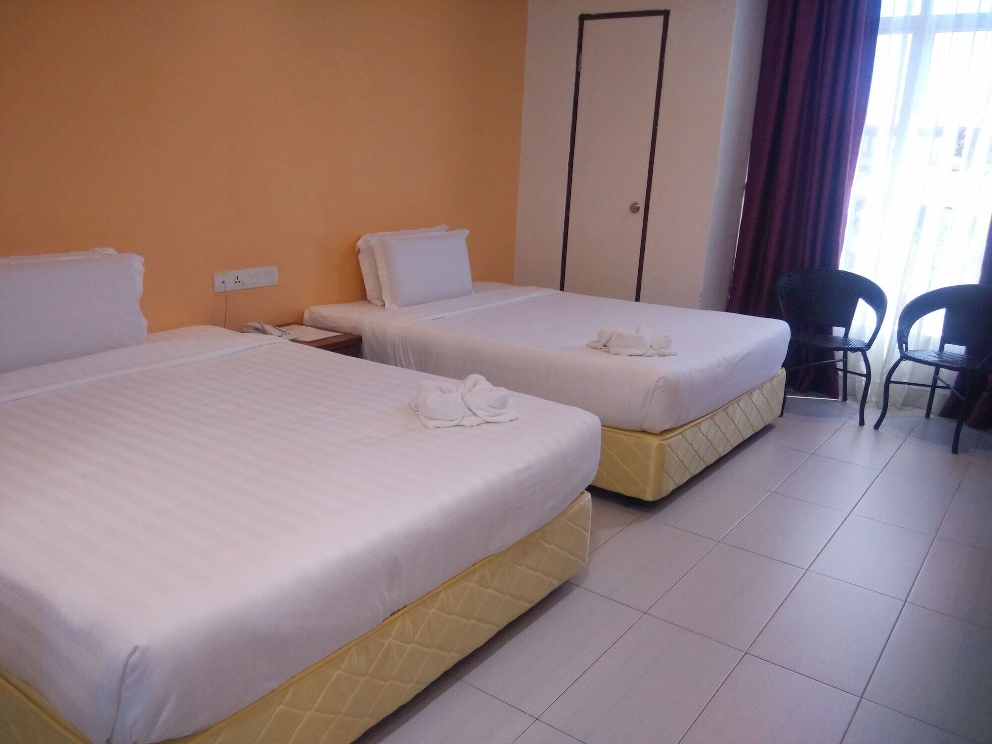 A hotel room with two beds, a desk, and a chair.
