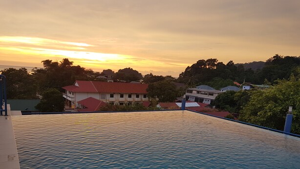 An infinity pool with a view of houses and trees during sunset. - MNY Hotel & Resort (Pangkor Island)