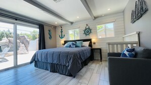 A bedroom with a bed, a nightstand, a chair, and a view of the outdoors. - ULTIMATE PRIVATE WATER PARK & POOL Next Disneyland (Anaheim)