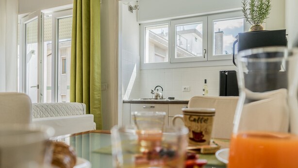 A dining area with a table set for breakfast, including a coffee cup and orange juice. - Conte Rosso Apartments ARCA (Mestre)