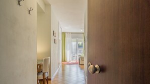 A hallway leading to a dining area with a wooden door, a chair, and a table. - Conte Rosso Apartments ARCA (Mestre)