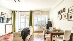 A cozy living room with a sofa, a dining table with chairs, a TV, and a kitchen in the background. - Conte Rosso Apartments ARCA (Mestre)