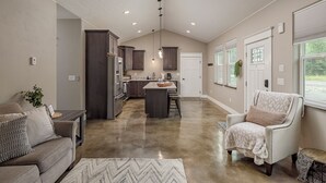 A spacious living area with a sofa, a chair, a kitchen island, and a dining table. - Stoneridge Place Cottage #2 - Vacation or Executive Retreat 2BR 2BA Garage! (Wasilla)