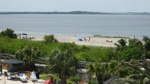 A beach with a clear view of the sea, a fenced area with outdoor seating, and lush greenery. - ABSOLUTELY AMAZING VIEW! (Tybee Island)