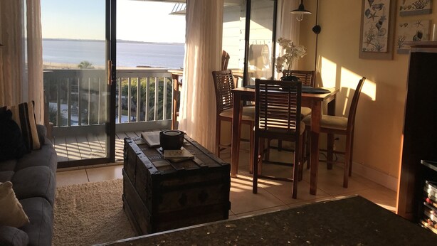 A living room with a view of the sea, a dining area with chairs and a table, and a wooden chest of drawers. - ABSOLUTELY AMAZING VIEW! (Tybee Island)