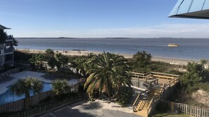 A beach view with a wooden deck, palm trees, and a boat on the water. - ABSOLUTELY AMAZING VIEW! (Tybee Island)
