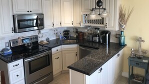 A kitchen with white cabinets, stainless steel appliances, a granite countertop, and pendant lighting. - ABSOLUTELY AMAZING VIEW! (Tybee Island)
