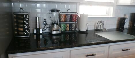 A kitchen with white cabinets, a black countertop, and a window.