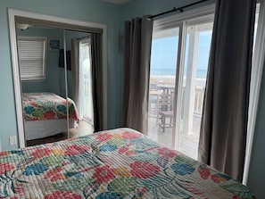 Une chambre avec un grand lit, un plus petit lit et un balcon donnant sur la plage.