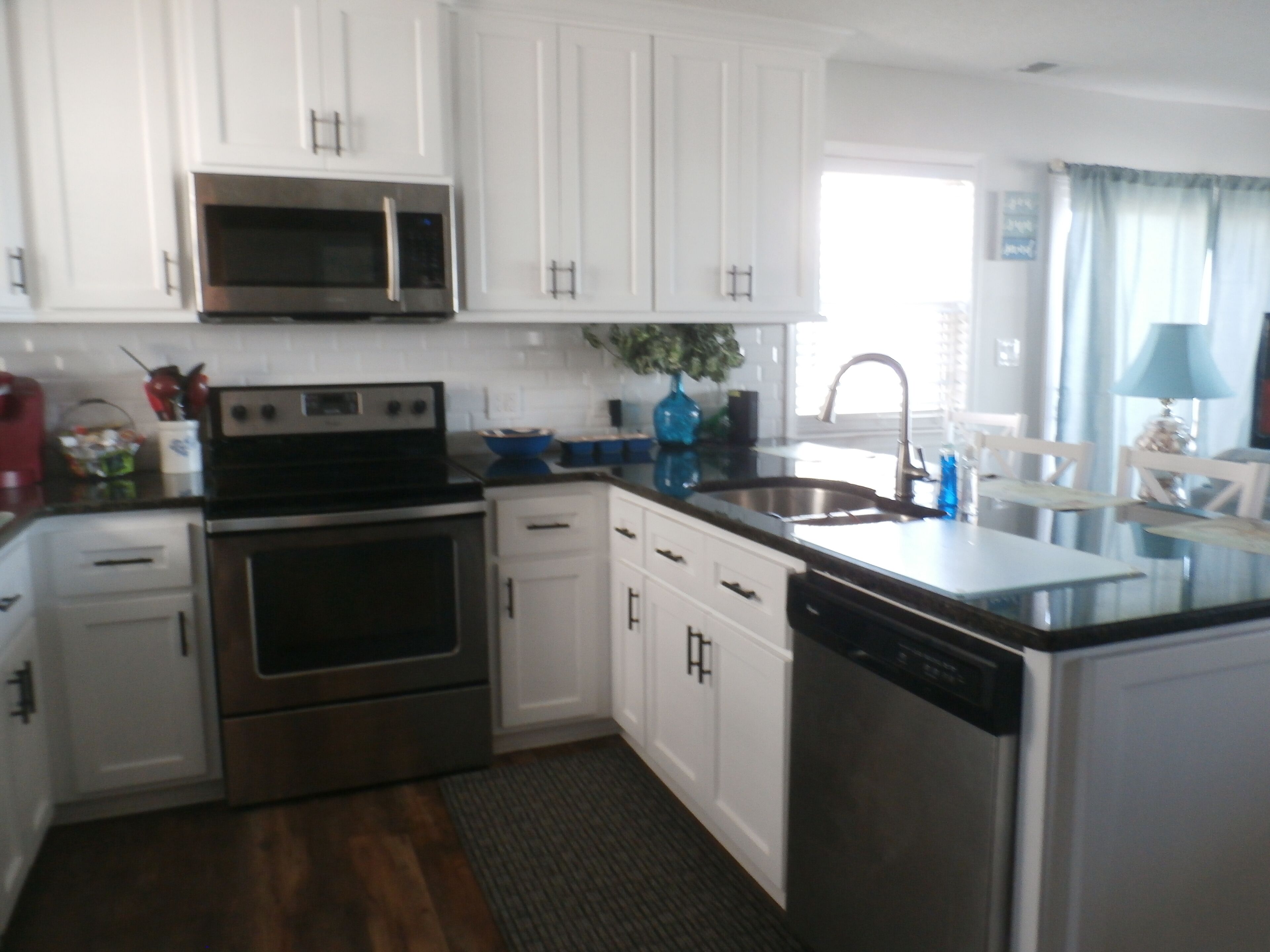 A modern kitchen with white cabinets, stainless steel appliances, and a built-in dishwasher.
