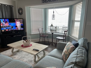 Un salon avec un téléviseur, une table sur laquelle se trouve un panier et un canapé.
