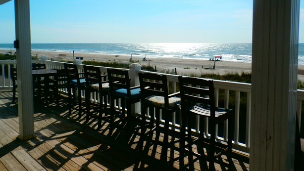 A wooden deck with chairs overlooking a beach. -  Ocean Lakes / Oceanfront /   5 bed/ water park /slps 14 (myrtle beach)