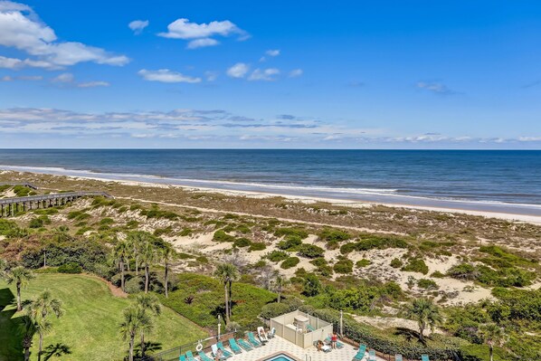 A beachfront property with a pool, lounge chairs, and a view of the ocean.