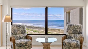 Una habitación con dos sillas mirando a un ventanal con vista al océano.
