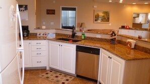 A kitchen with white cabinets, a dishwasher, a granite countertop, and a window above the sink.