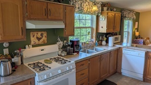 A kitchen with wooden cabinets, a stove, a sink, and a dishwasher. - Ponderosa Cabin with Private Hot Tub - Near Mt Rushmore and Hills Attractions (Custer)