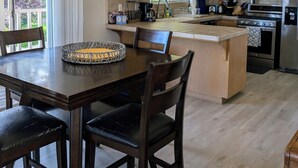 Een moderne keuken met houten kasten, een centraal eiland en een eethoek met tafel en stoelen.