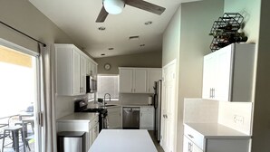 Una cocina moderna con armarios blancos, una isla central y un comedor con mesa y sillas.