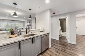 Enjoy cooking in this well-lit kitchen with a granite countertop, stainless steel appliances, and ample storage.