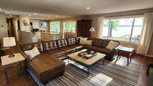 A spacious living room with a large L-shaped brown leather sofa, a coffee table, and a striped rug.
