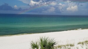 Une plage d’où l’on a une vue dégagée sur l’océan et où l’on peut admirer un arc-en-ciel dans le ciel.