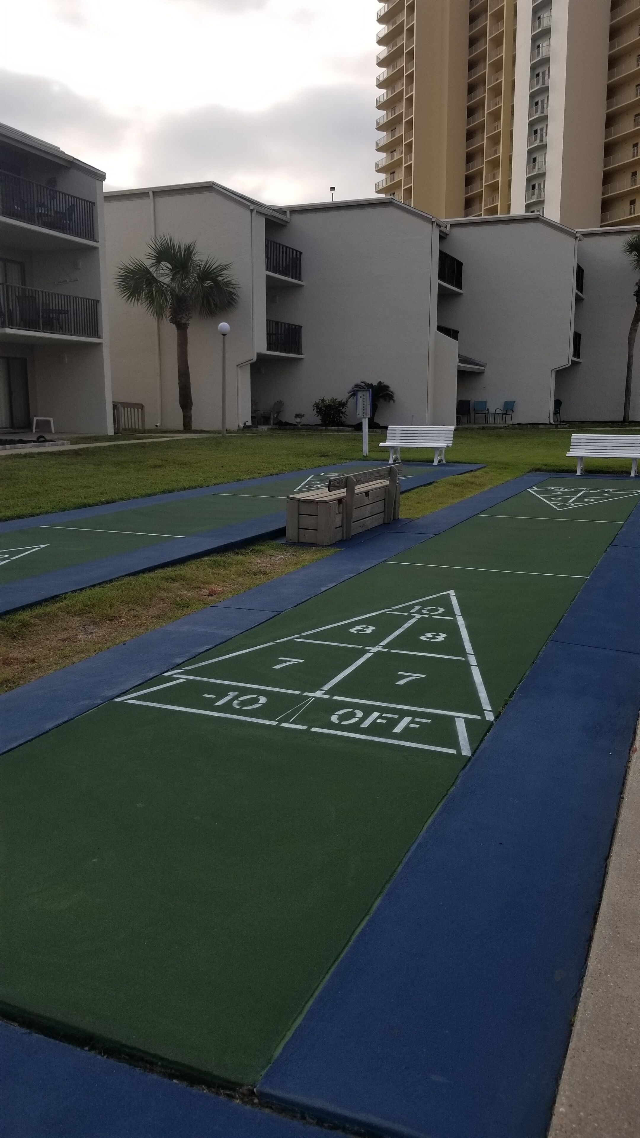 Camp de bitlles amb una marca 'GO OFF', envoltat d'una zona verda i un edifici amb balcons.
